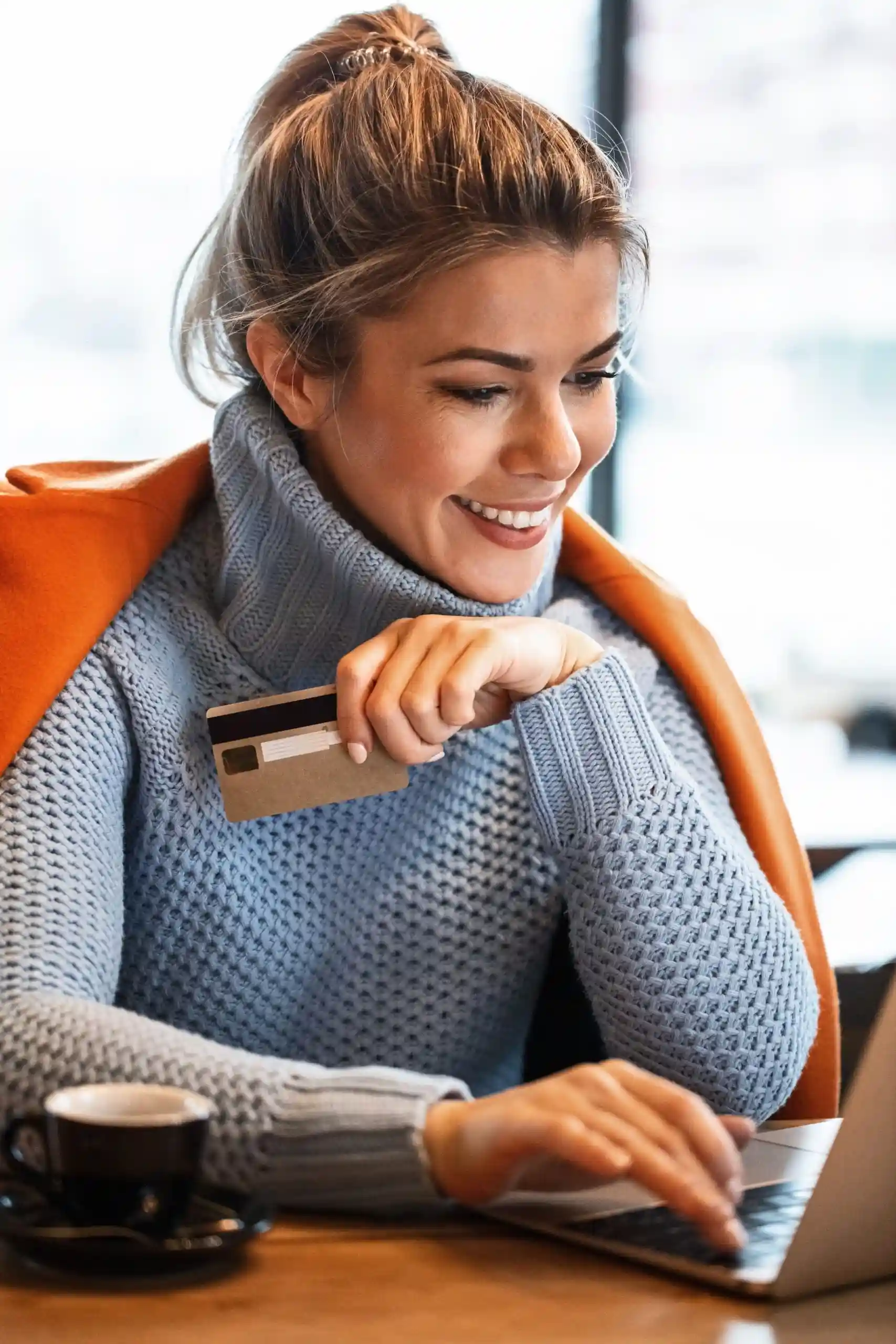 Joyful Shopping Experience - Delighted woman holding a credit card in her hand while making a purchase, expressing happiness and satisfaction with the buying process.